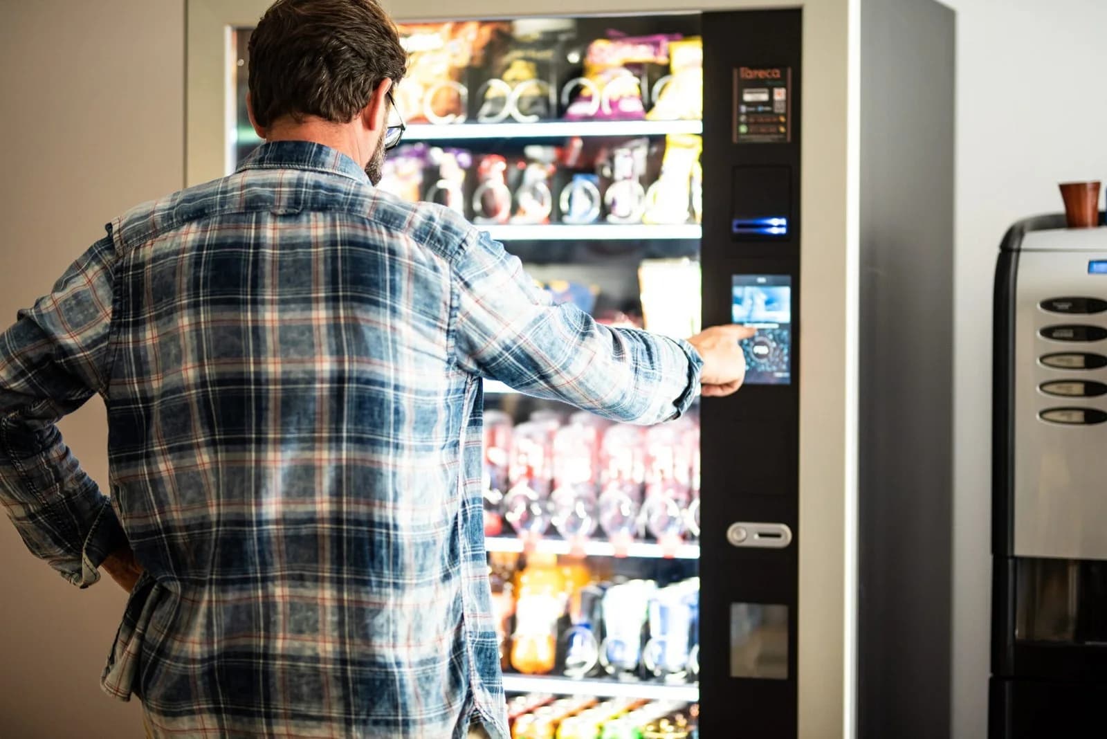 A man choosing snacks at an office vending machine